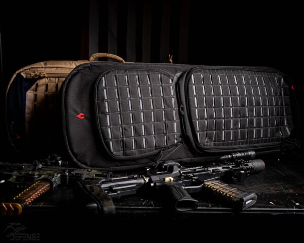 Two tactical bags are displayed side by side on a dark surface surrounded by two rifles and accessories showcasing a military or defense context emphasizing preparedness and functionality.