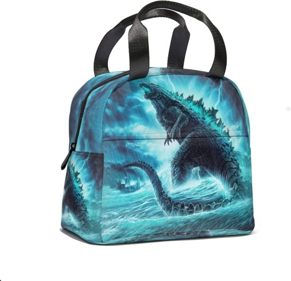 A blue and black lunch bag featuring an illustration of Godzilla rising from turbulent ocean waters with lightning in the background creating a dramatic scene.