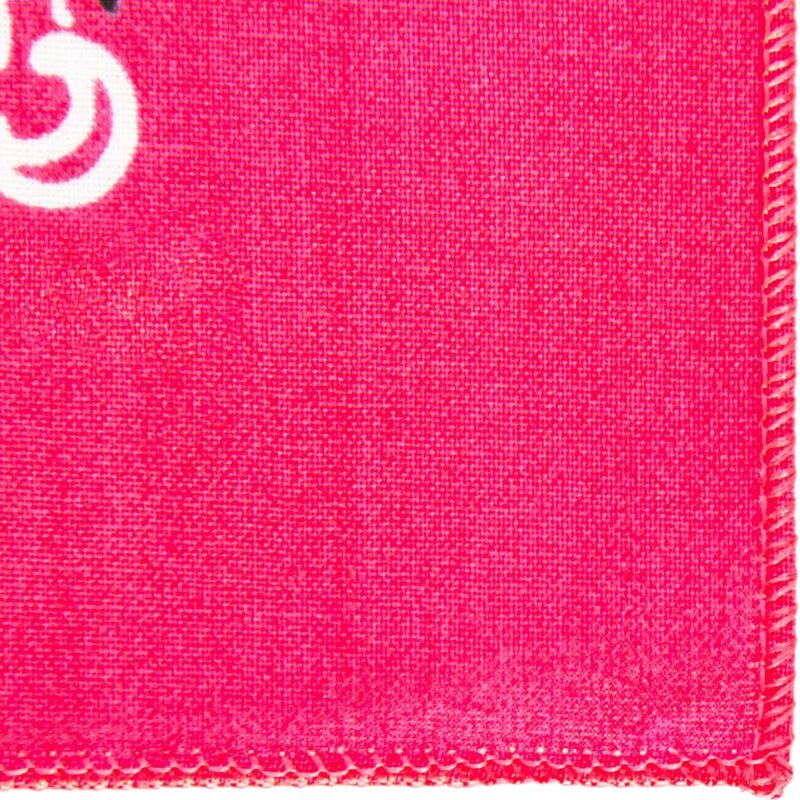 A vibrant pink fabric features a white circular design in the top left corner against a textured background with visible stitches along the edge. The setting appears to be a close-up view.