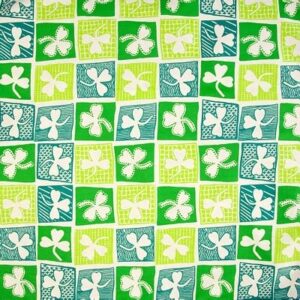 A patterned fabric features a grid of squares in varying shades of green and blue each containing a white clover design creating a vibrant and playful textile.