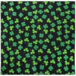 A square black cloth features a pattern of green clovers scattered evenly across its surface creating a vibrant contrast designed for festive occasions or celebrations.