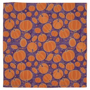 A vibrant purple fabric covered in a pattern of various orange pumpkins with some swirling vines and small circles creating a festive autumnal atmosphere.