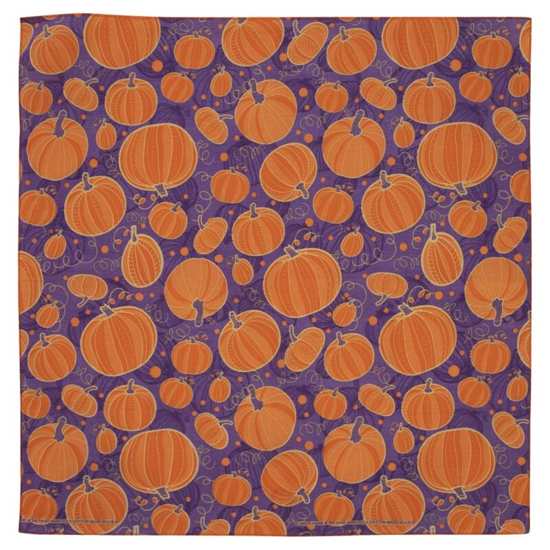 A vibrant purple fabric covered in a pattern of various orange pumpkins with some swirling vines and small circles creating a festive autumnal atmosphere.