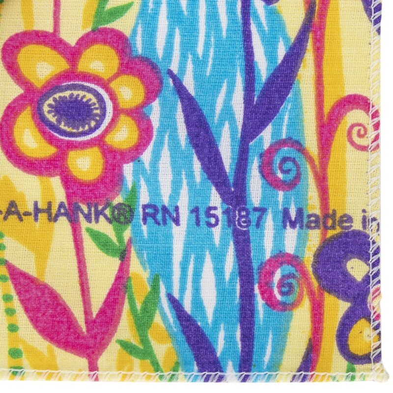 A colorful fabric features vibrant flowers and swirls against a yellow background. Text reads "A-HANK® RN 1587 Made in." The design exudes a playful  cheerful aesthetic.
