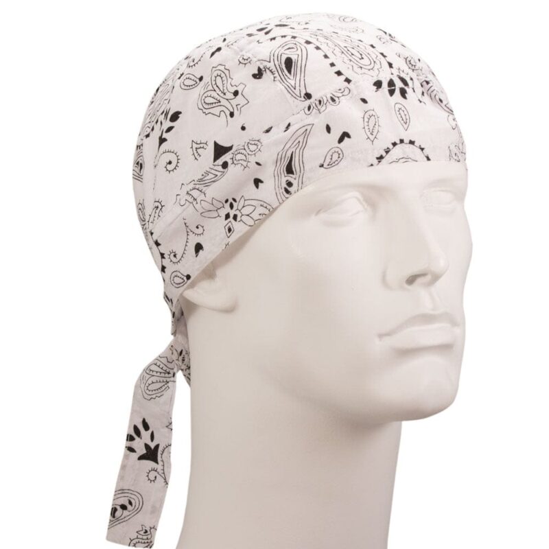 A white bandana with black paisley patterns is tied around a mannequin’s head  resting snugly in place  showcasing its design in a neutral setting against a plain background.