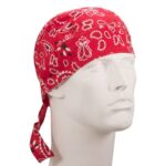 A red bandana with a paisley pattern adorns a white mannequin head positioned upright against a neutral background emphasizing the bold color and design of the accessory.