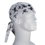 A white bandana with black skull and crossbones patterns is tied around the head of a mannequin facing sideways in a neutral setting without any additional context or distractions.