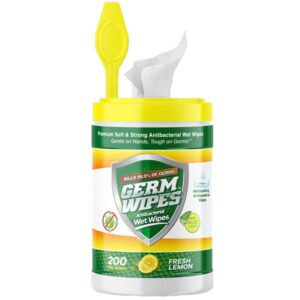 A cylindrical container of antibacterial wet wipes is being opened with a white wipe partially pulled out the top. The container features bright yellow and green colors and a fresh lemon scent.